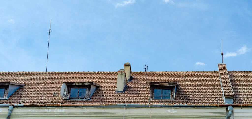 Toiture ancienne en tuiles avec cheminées en pierre